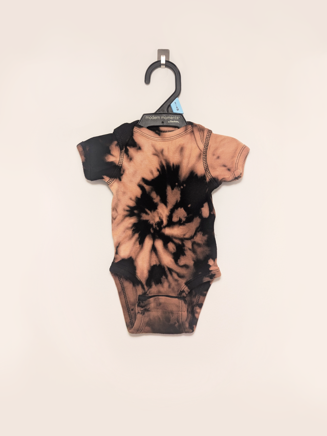 Black baby onesie with hand-bleached spiral design in the center