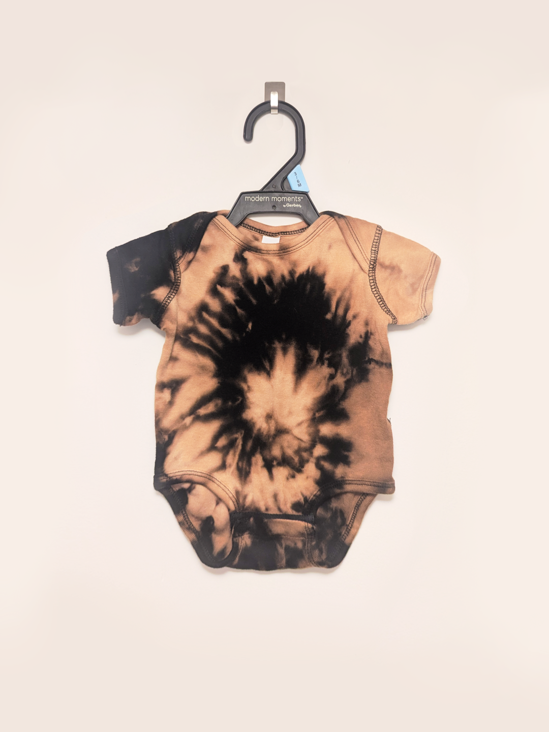 Black baby onesie with hand-bleached ringed design in the center