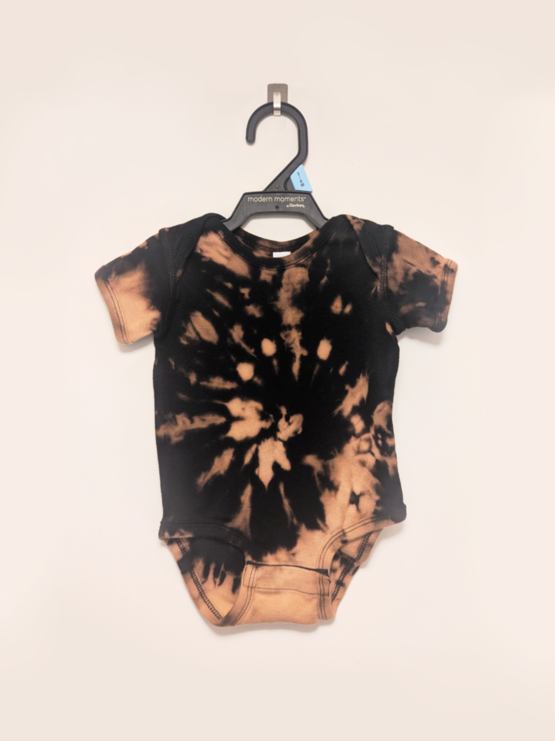 Black baby onesie with hand-bleached ringed design in the center