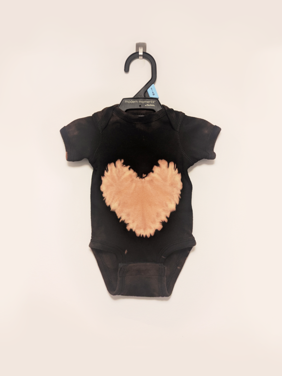 Black newborn onesie with hand-bleached heart design in the center