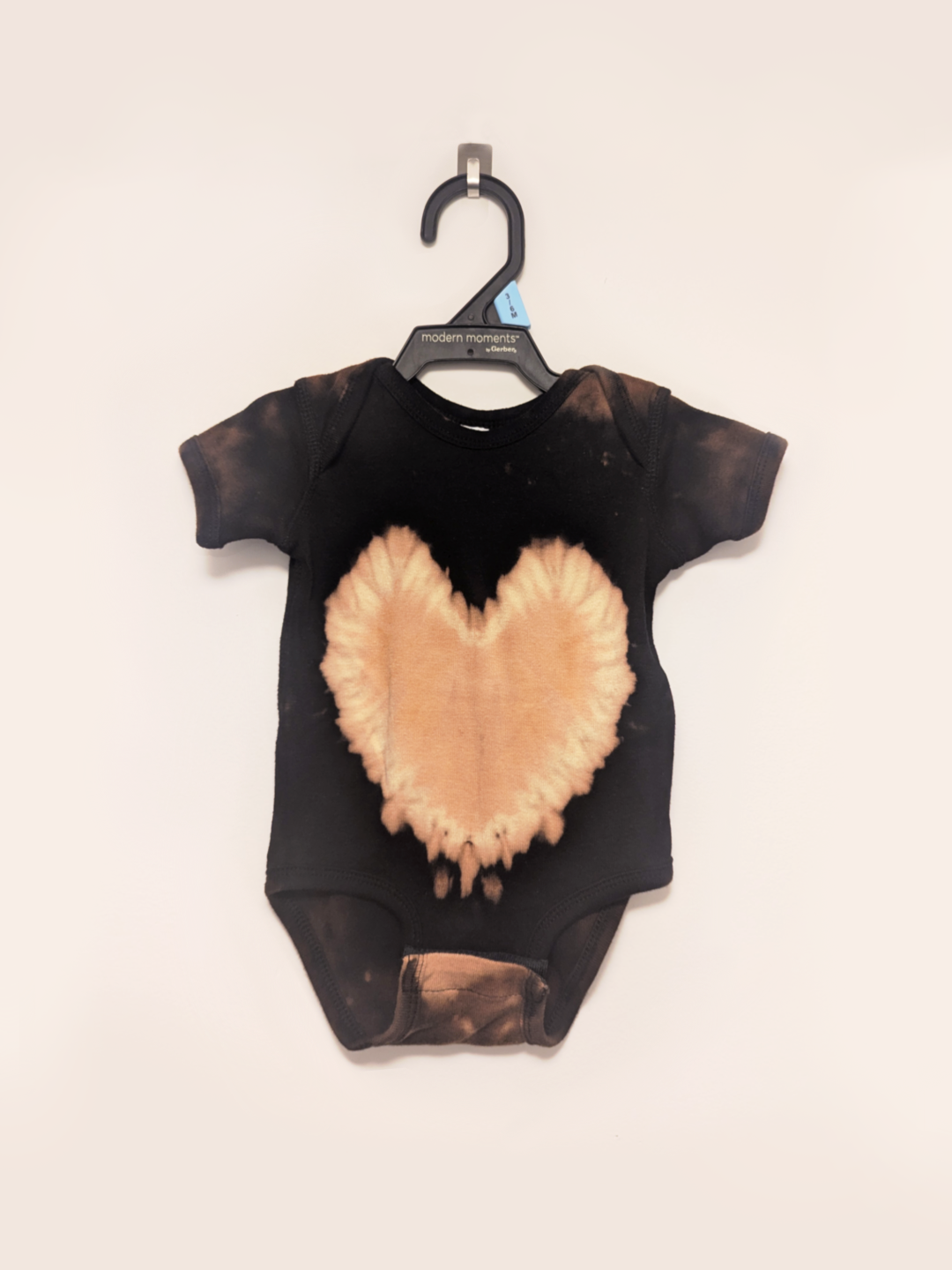 Black baby onesie with hand-bleached heart design in the center
