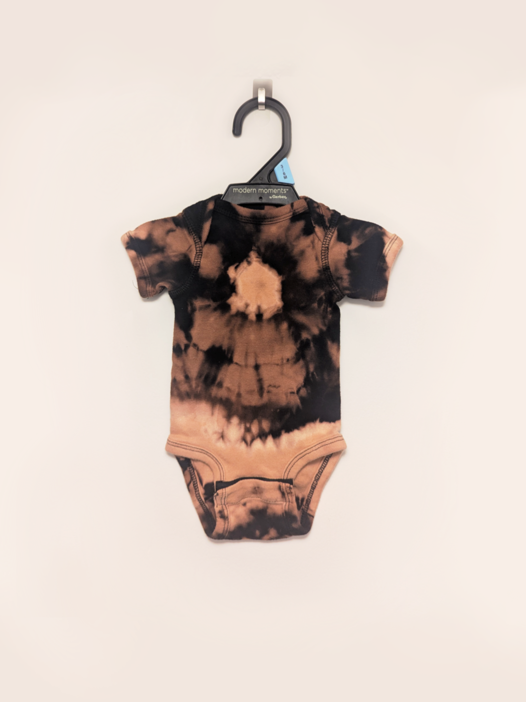 Black baby onesie with hand-bleached ringed design in the center