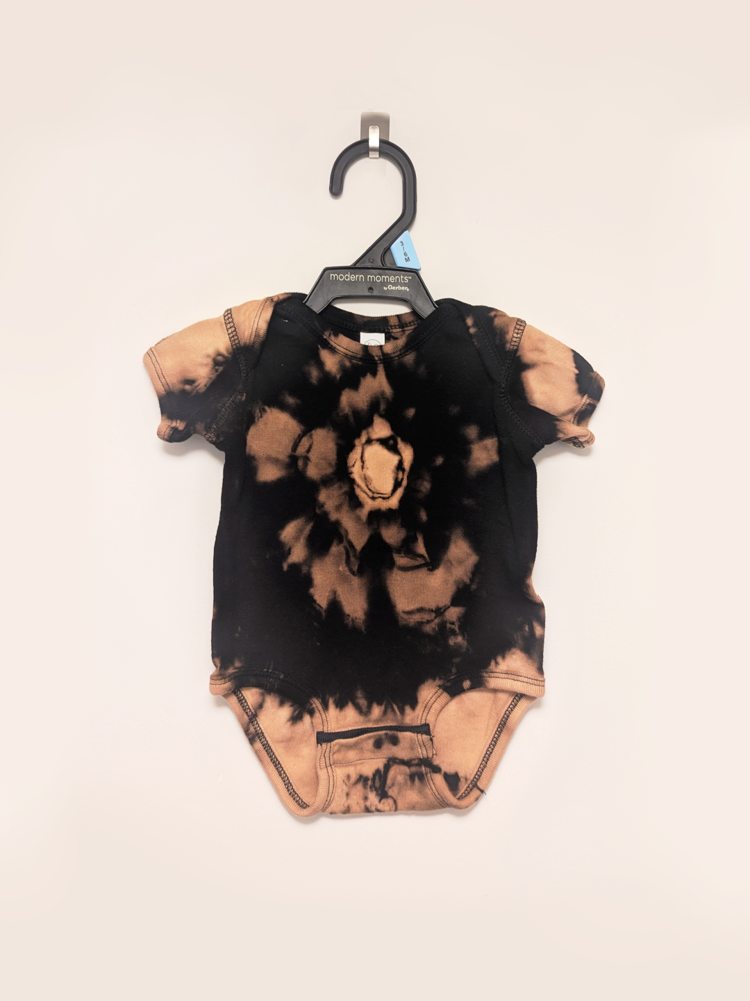 Black baby onesie with hand-bleached ringed design in the center