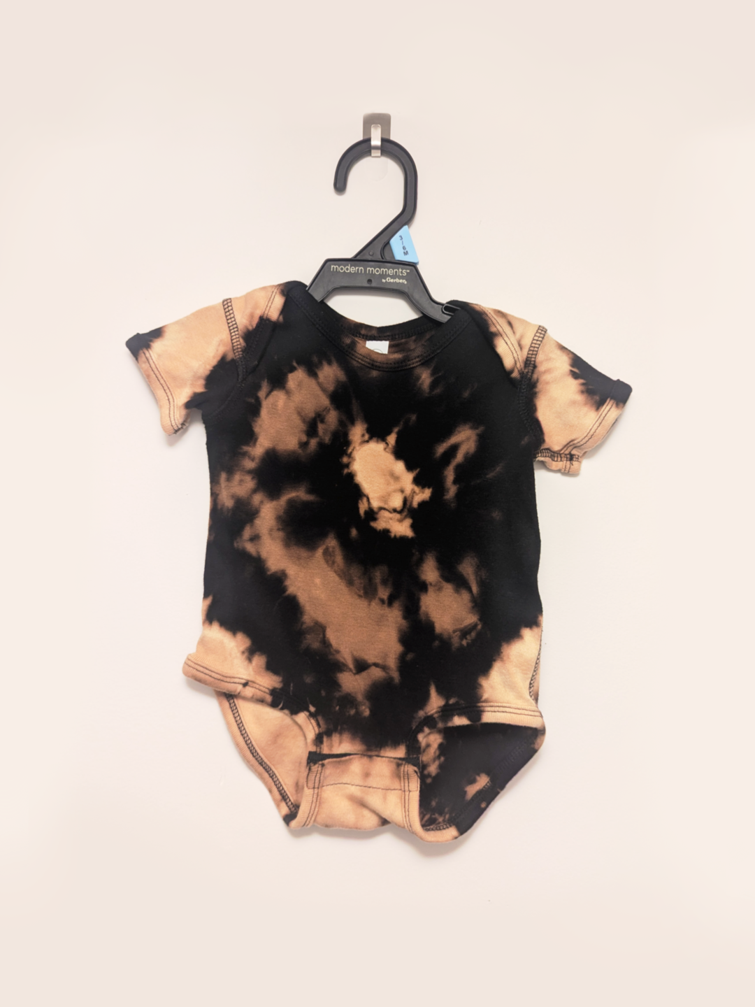Black baby onesie with hand-bleached ringed design in the center